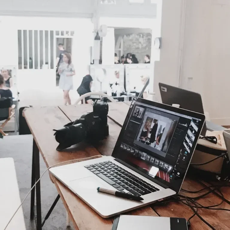 Fotografie Workshop in Münster Ein Tisch mit einem Laptop, einer Kamera und Schreibutensilien in einem kreativen Raum.