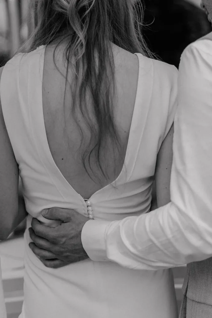 Hochzeitsreportage im Garten in Münster Ein Paar umarmt sich, der Fokus liegt auf dem Rücken des Kleides der Frau.