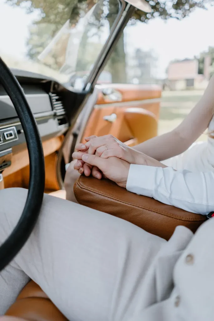 Hochzeitsreportage in Münster mit Oldtimer Händchen haltende Paare in einem Oldtimer mit einem natürlichen Hintergrund.